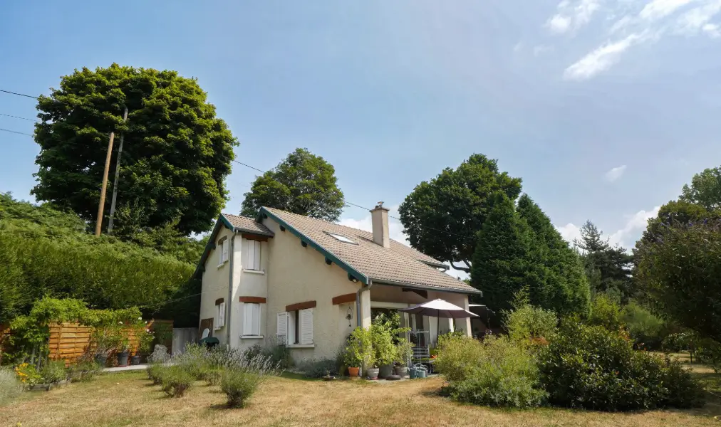 Maison individuelle avec jardin arboré et terrasse couverte, façade claire et toiture en tuiles, photographiée en été sous un ciel bleu – photographie immobilière Focus&Toit à Tournon-sur-Rhône.
